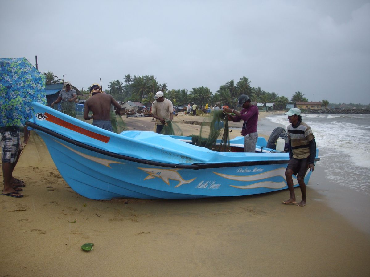 Fishermen with their boat on a Sri Lankan beach